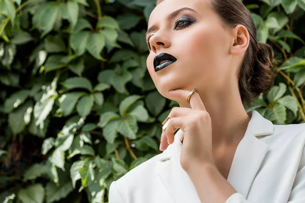 Jovem Elegante Jaqueta Branca Tocando Rosto Com Folhas Verdes Fundo — Fotografia de Stock