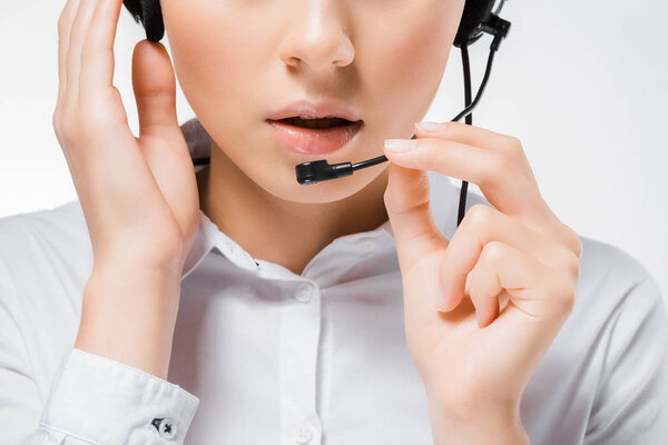 close up of young call center operator touching headset and speaking in microphone