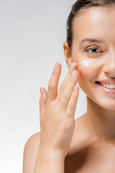 young beautiful woman applying white cream on cheek