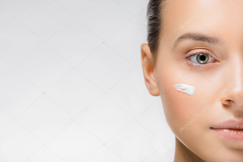 young woman with white facial cream on cheek