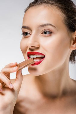 young beautiful woman with red lips biting chocolate piece clipart