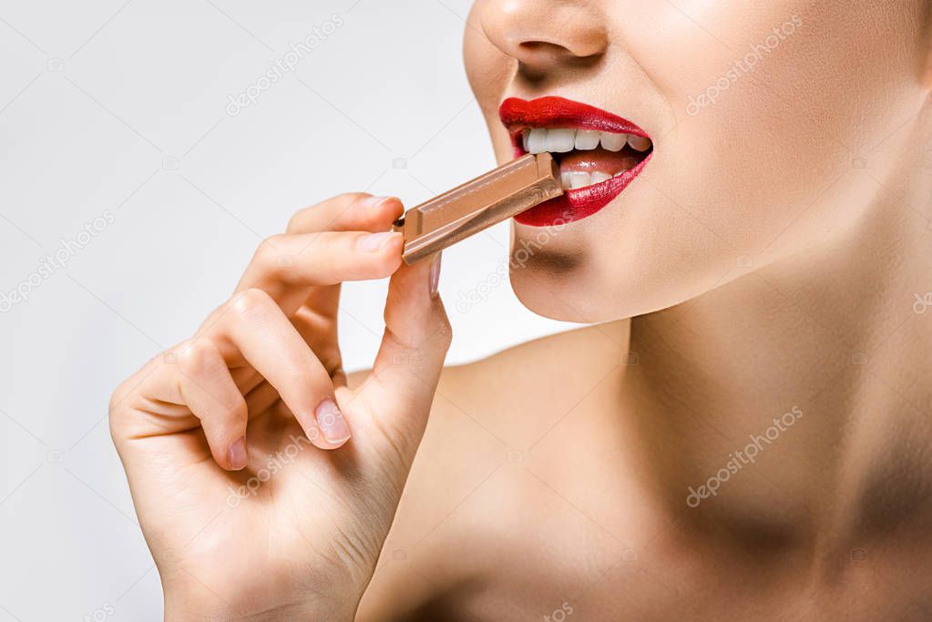 close up of young beautiful woman with red lips biting chocolate piece