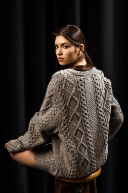 arkadan görünüşü yün gri süveterli bar siyah arka plan taburede oturan güzel kadın