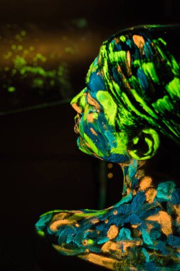 back view of model with colorful neon paints on body on black background clipart