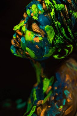 high angle view of woman painted with bright neon paints on black background clipart