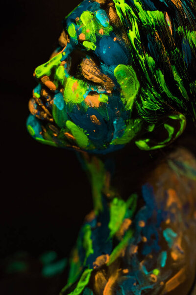 high angle view of woman painted with bright neon paints on black background