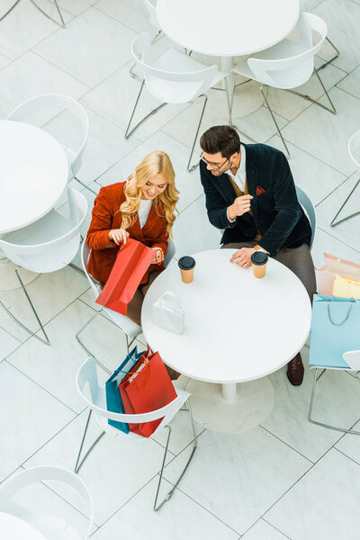 overhead view of fashionable couple with shopping bags sitting in cafe  