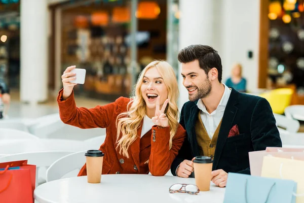 Stylish Shopaholics Showing Victory Sign Taking Selfie Smartphone Shopping Center — Free Stock Photo