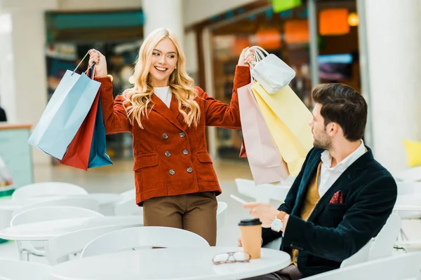 Happy Shopaholic Showing Shopping Bags Boyfriend Cafe Shopping Center — Stock Photo, Image