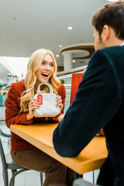 Excited Beautiful Girl Showing Bag Sale Tag Boyfriend — Free Stock Photo