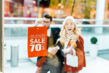 selective focus of super sale with 70 percents discount and couple in shopping mall clipart
