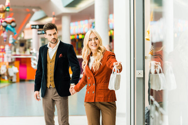 young beautiful woman showing showcase to boyfriend in shopping center