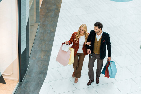 overhead view of young couple with shopping bags walking in shopping mall