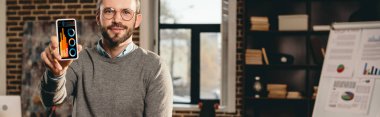 casual işadamı loft Office ekranda grafik ile akıllı telefon tutarak görünümünü kırpılmış
