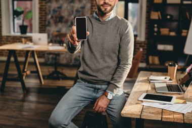 casual işadamı smartphone boş ekran ile çatı ofiste tutan görünümünü kırpılmış