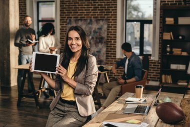 Casual işkadını holding tablet ile boş perde arkasında çalışan meslektaşları ile çatı ofiste