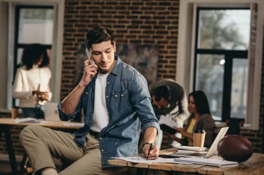 arka plan meslektaşları ile Smartphone cep telefonu ile modern loft Office konuşan genç adam 