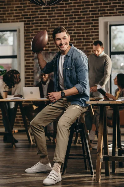 Χαρούμενος Νεαρός Άνδρας Κρατώντας Την Μπάλα Του Ράγκμπι Στο Γραφείο — Δωρεάν Φωτογραφία