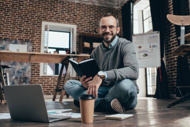 bilgisayar ile katta oturan ve modern loft Office proje üzerinde rahat işadamı gülümseyen