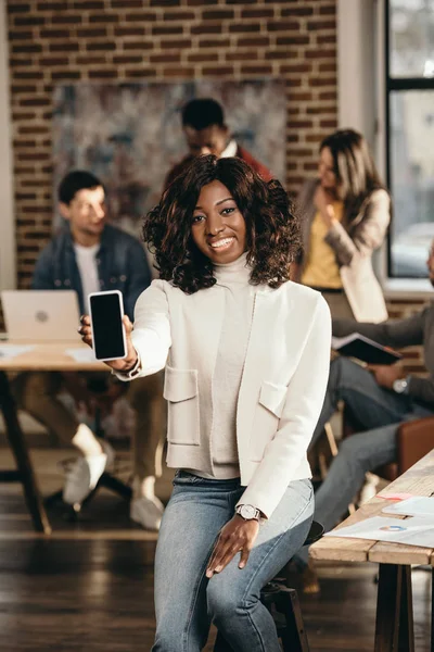 Lächelnde Afrikanisch Amerikanische Gelegenheitsunternehmerin Zeigt Auf Smartphone Mit Leerem Bildschirm — kostenloses Stockfoto