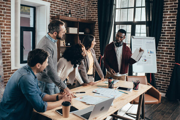 focused multiethnic group of colworkers having meeting and discussing together new project in modern loft office
