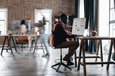 hareket meslektaşları ile masa başında çalışma rahat Afrikalı-Amerikalı işadamı bulanıklık modern loft ofiste