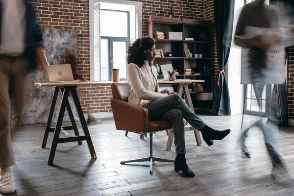 Afro Amerikaanse Zakenvrouw Heaphones Zitten Stoel Met Collega Beweging Vervagen — Stockfoto