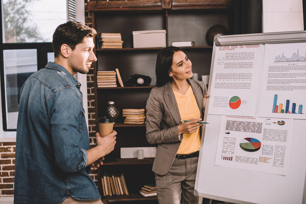 successful couple of colleagues discussing project using graph in loft office