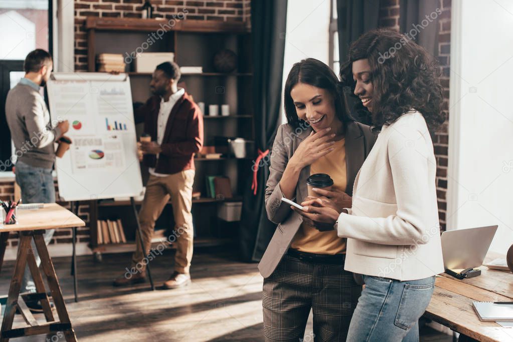 casual businesspeople using smartphone and working together on project in loft office