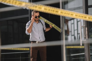  Çapraz satırında tutan güneş gözlüğü düzleştirme erkek dedektif