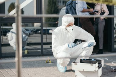 koruyucu elbise ve lateks eldiven kanıt, bir büyüteç aracılığıyla arıyorum erkek kriminoloji uzmanı