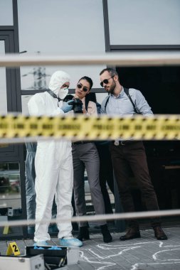 criminologist showing photo from crime scene to two detectives clipart