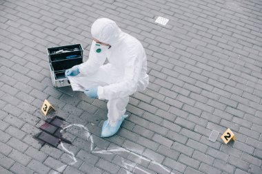 male criminologist in protective suit and latex gloves explore evidence at the crime scene clipart