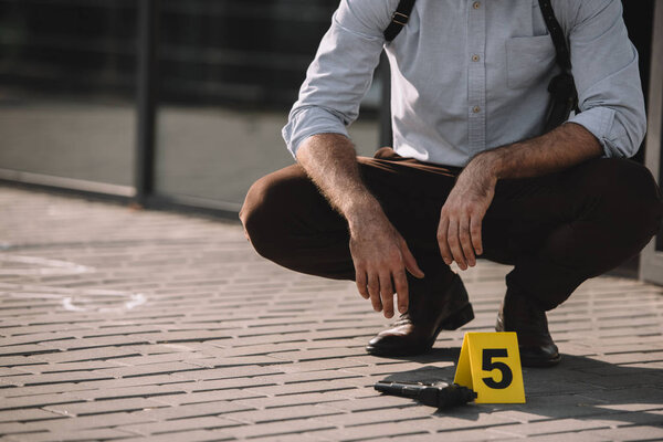 cropped view of male detective sitting near evidence