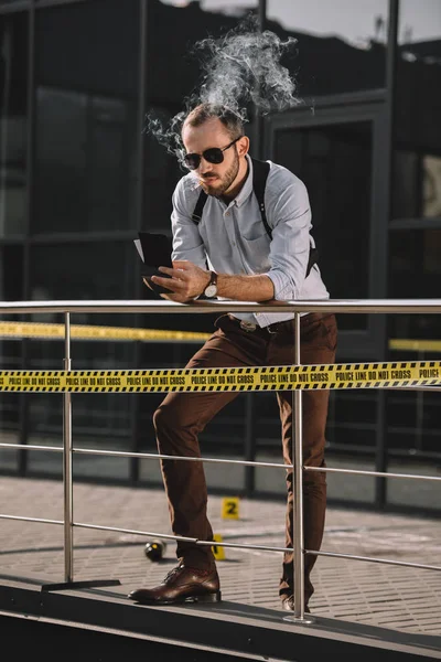 Male Detective Smoking Looking Notes Leaning Fence — Free Stock Photo