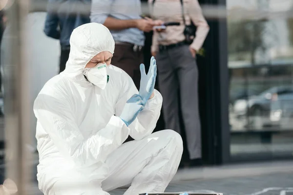 男性犯罪学家在保护戴乳胶手套与裁剪侦探背后 — 图库照片