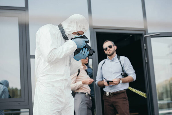 Criminologist making photo on camera with two detectives behind him