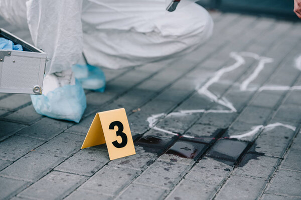 частичный взгляд криминалиста, сидящего рядом с пронумерованными уликами
