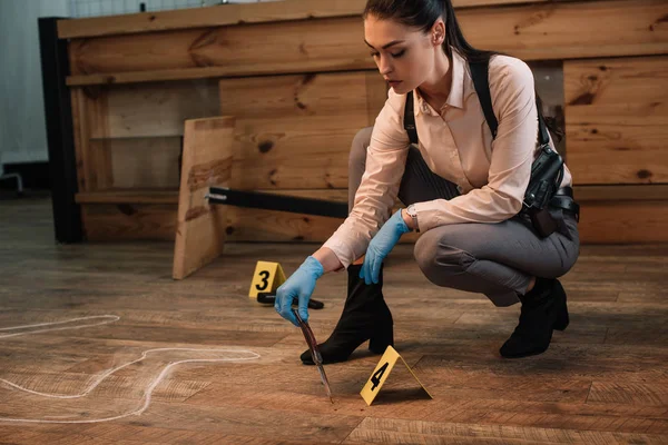 concentarted female detective collecting evidence at crime scene