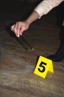cropped view of hand examining evidence at crime scene clipart