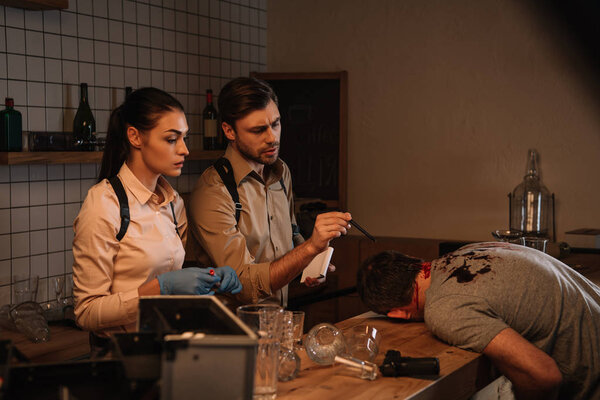 серьезные женщины и мужчины детективы используют набор для сбора улик и расследования трупа на месте преступления
 