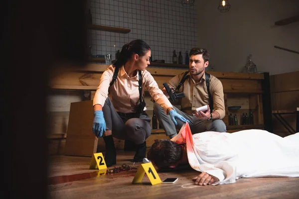 深刻な女性と男性探偵の証拠マーカーした犯罪現場で死体の調査 — ストック写真