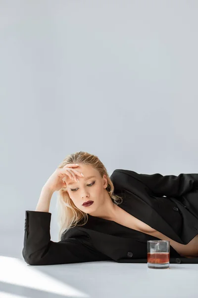 Schönes Modell Schwarzen Trendigen Anzug Auf Grau Liegend Mit Glas — kostenloses Stockfoto
