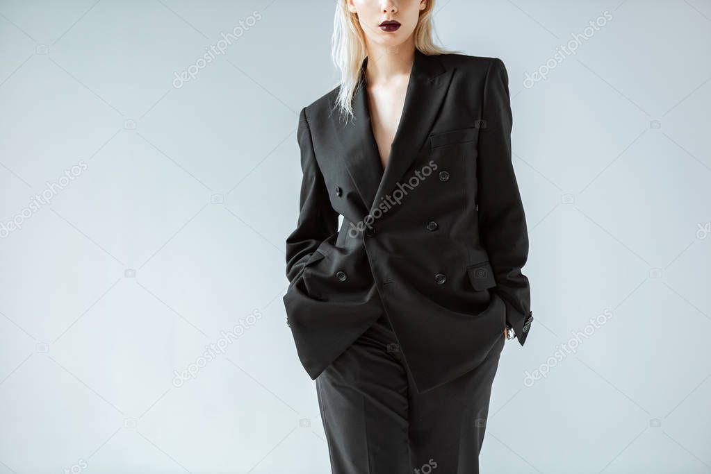 cropped view of fashionable girl posing in black suit isolated on grey