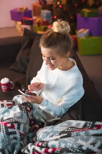 Kanepede Oturan Noel Zamanda Smartphone Kullanarak Gülümseyen Genç Sarışın Kadın — Ücretsiz Stok Fotoğraf