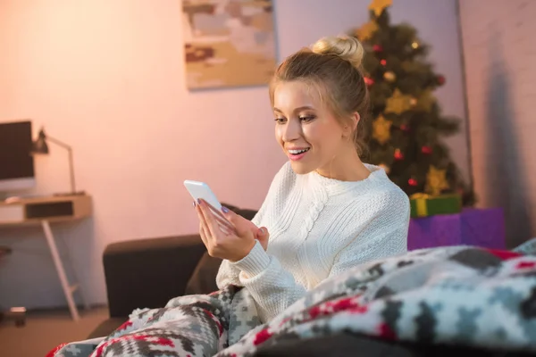 Fericit Tânără Blondă Femeie Stând Canapea Folosind Smartphone Timpul Crăciunului — Fotografie de stoc gratuită