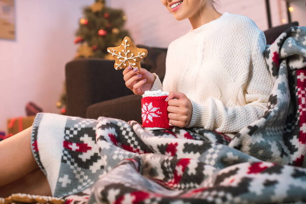 woman in blanked holding christmas gingerbread cookie and cup with hot cocoa