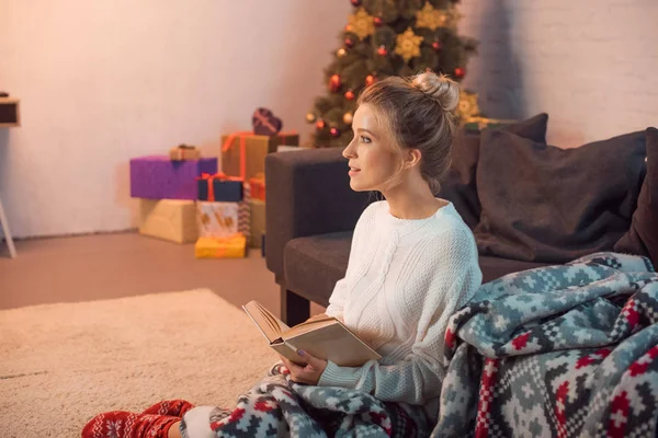 笑っている女の子を魅力的なクリスマスイブに家で本を読んで — ストック写真