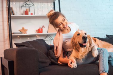 kanepede oturan ve golden retriever köpek Noel zamanda sarılma güzel gülümseyen genç sarışın kadın