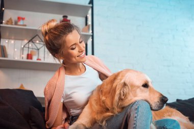 kanepede oturan ve golden retriever köpek Noel zamanda sarılma güzel mutlu sarışın genç kadın